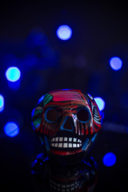 Cranio messicano dia de muertos in ceramica su sfondo scuro con luci