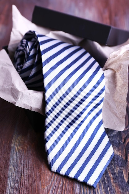 Cravatta a righe in scatola sul primo piano della tavola di legno