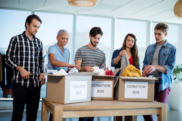 Creative team aziendale vestiti di smistamento nella casella di donazione in ufficio