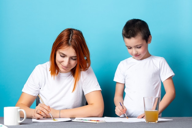 Creatività dei bambini. Madre e figlio dipingono con vernice su sfondo blu