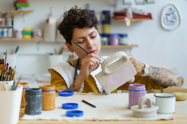 Creativo artigiano donna pittura brocca in ceramica processo artistico in ceramica studio ceramista al lavoro