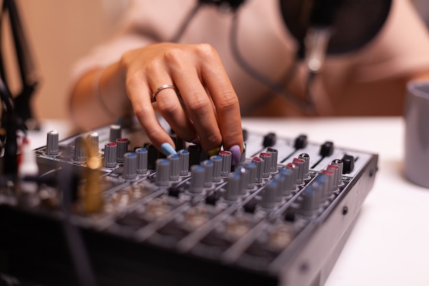 Creatore di contenuti che controlla l'audio sul mixer dj per un podcast migliore