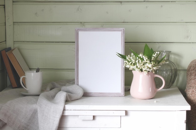 Creatore di scene di cottage primaverili Vecchi libri un mockup vuoto di una cornice fotografica verticale in legno in piedi contro un muro di cartone