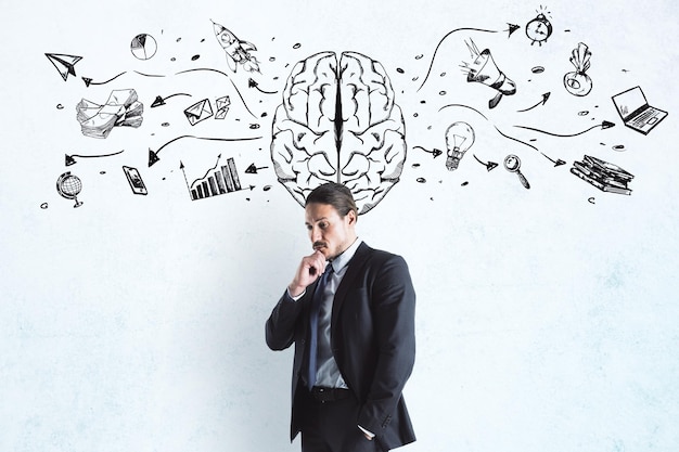 Creazione di idee e concetti di brainstorming con un uomo d'affari pensieroso alla lavagna con schizzo di cervello e icone aziendali sullo sfondo
