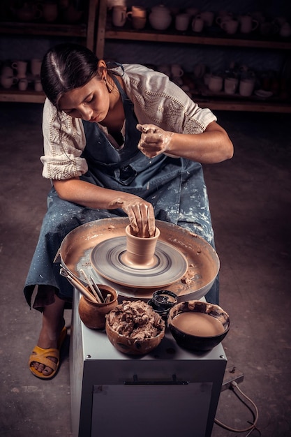 Creazione di un barattolo o vaso. Maestro coccio. Fare una brocca di argilla. Lo scultore in officina realizza una brocca con un primo piano di terracotta. Tornio da vasaio. Concetto di ceramica.