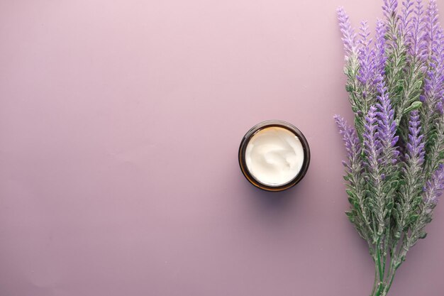 Crema cosmetica alle erbe in un contenitore su sfondo viola