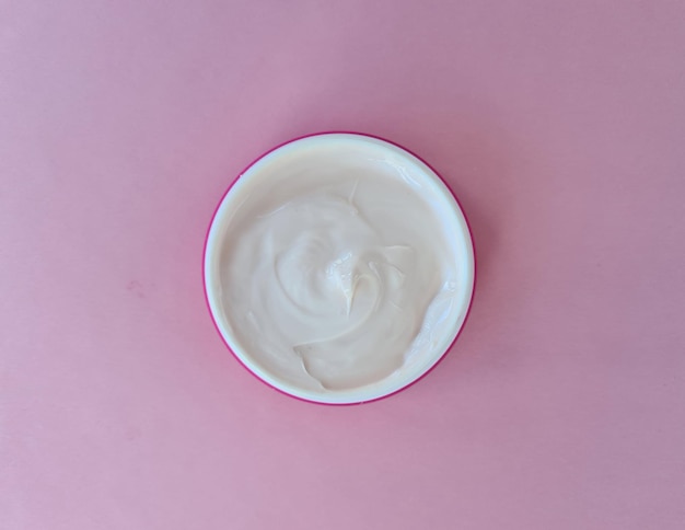 Crema cosmetica antietà bianca su sfondo rosa