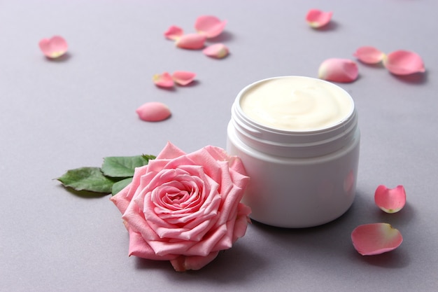 Crema cosmetica e fiori su un primo piano colorato del fondo