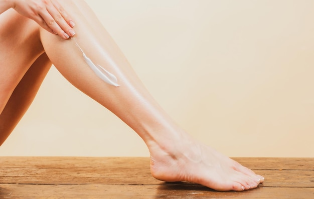 Crema cosmetica sulla gamba della donna con pelle morbida e pulita che applica crema idratante sulle gambe cellulite o formica