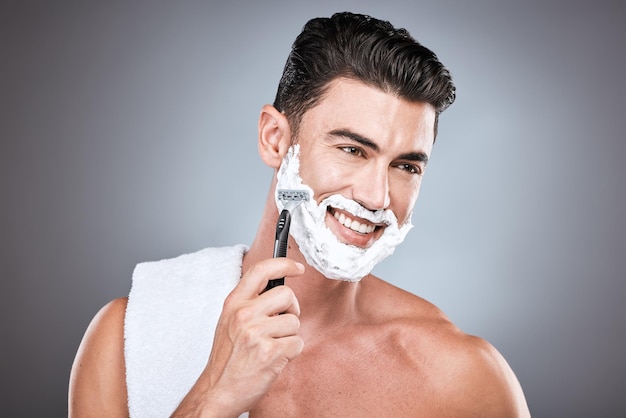 Crema da barba viso e uomo con rasoio in studio isolato su sfondo grigio Depilazione pulizia e pensiero modello maschile con prodotto viso schiuma o gel da radere per il benessere e la depilazione