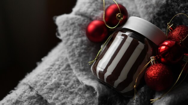 Crema di cioccolato dolce nel barattolo sullo sfondo di Natale con palline rosse