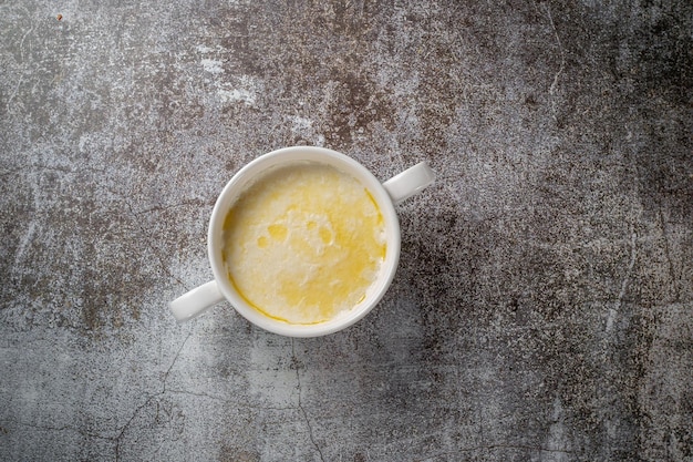 Crema di grano, budino di semola con burro in una tazza bianca contro un tavolo di pietra grigia. Una sana colazione al ristorante