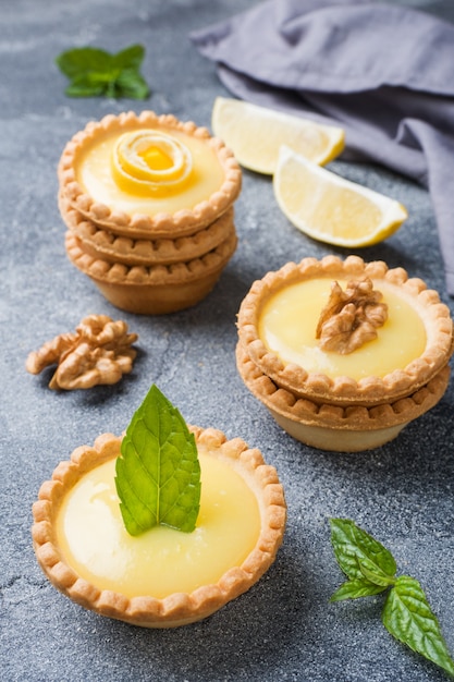 Crema di limone fatta in casa in tortine con foglie di menta e limone fresche.