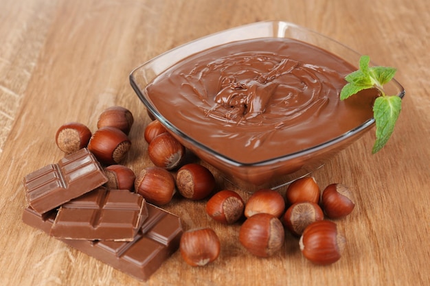 Crema di nocciole al cioccolato dolce con noci intere e menta su fondo di legno