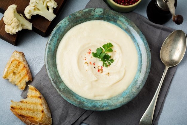 Crema di zuppa bianca vegetariana di cavolfiore in un piatto di ceramica vintage