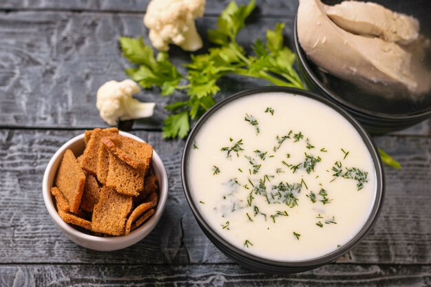 Crema di zuppa di cavolfiore e una ciotola di cracker su un tavolo di legno