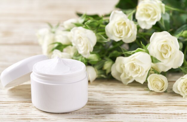 Crema idratante per pelli sensibili, cosmetici termali e prodotti per la cura della pelle puliti naturali su uno sfondo di rose bianche.