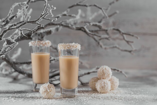 Crema irlandese o liquore al caffè con palline sane di cocco fatte in casa e fiocchi di cocco su superficie chiara