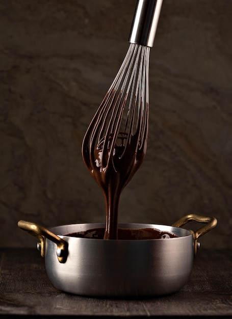 Crema liquida al cioccolato versata da una frusta in un mestolo