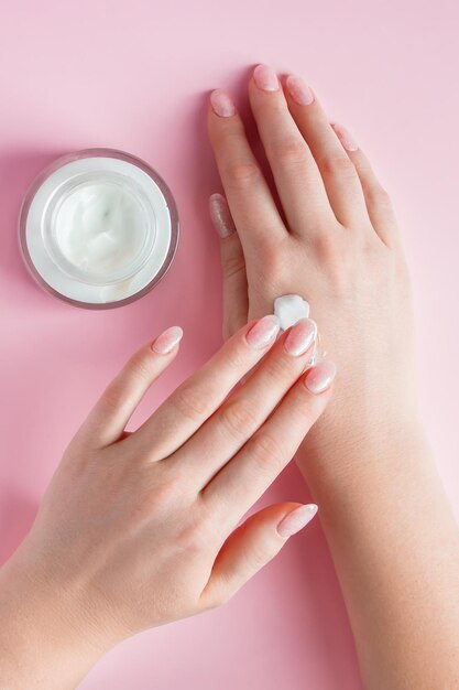 Crema nutriente e belle mani femminili su sfondo rosa Concetto di cura della pelle Immagine per pubblicità e design