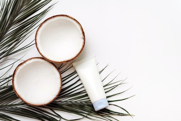 Crema per la cura della pelle con olio di cocco su sfondo bianco con foglie di palma e noci di cocco Concetto di trattamento del corpo e dei capelli
