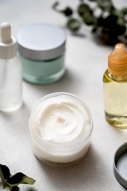 Crema per la cura della pelle e vasetti contagocce oli con prodotti cosmetici Concetto di bellezza e benessere Foglie di eucalipto