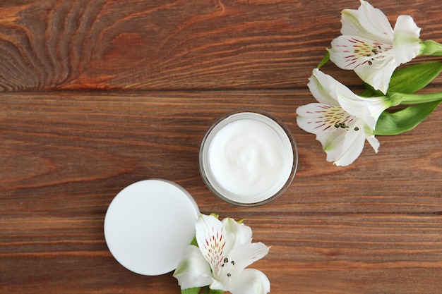 Crema per la cura e fiori su uno sfondo colorato vista dall'alto cosmetici per la cura della pelle