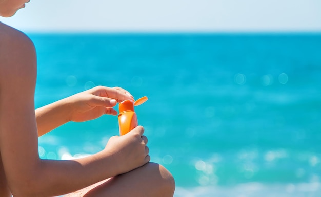 Crema solare nelle mani sulla spiaggia. Messa a fuoco selettiva.