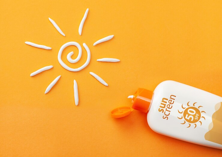 Crema solare su sfondo arancione. Bottiglia di plastica di protezione solare e crema solare bianca.