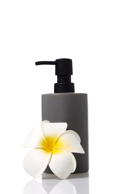 Crema spa bottiglia grigia Cura del corpo con fiore di plumeria sulla superficie della natura