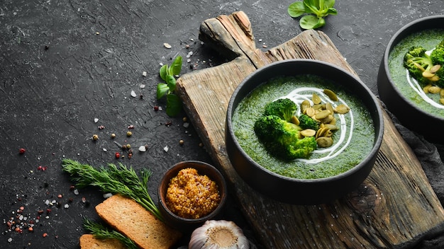 Crema verde di zuppa di broccoli e semi di zucca in una ciotola nera Vista dall'alto Spazio libero per il testo Stile rustico