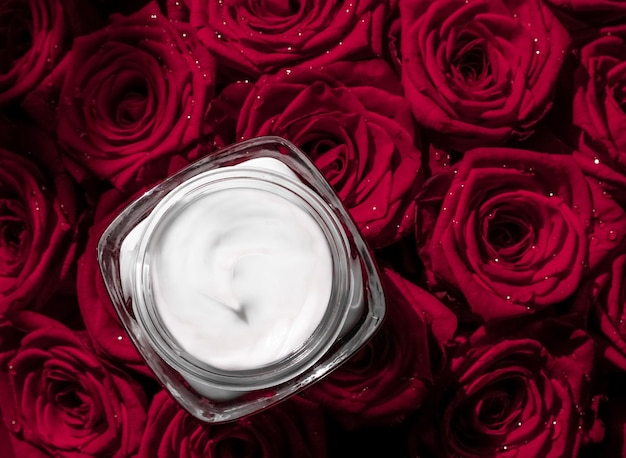 Crema viso idratante per la pelle e fiori di rose rosse prodotto cosmetico di lusso per la cura della pelle su sfondo floreale come design flatlay per le vacanze di marca di bellezza