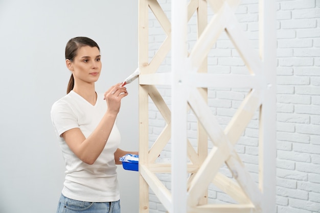 Cremagliera di legno della pittura della donna castana nella stanza vuota