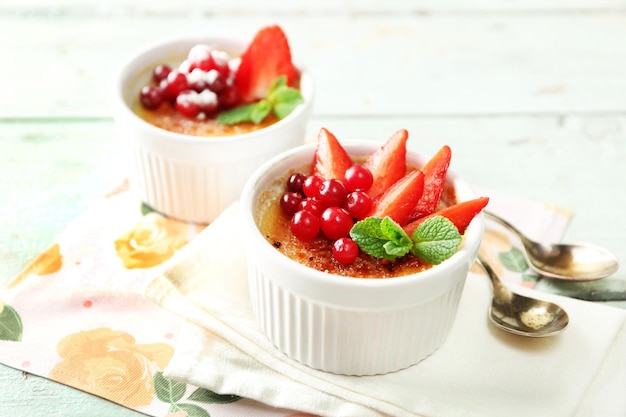 Creme brulée dessert con fragole fresche e foglie di menta su sfondo di legno colorato