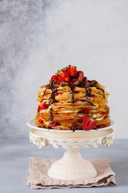 Crepe Cake al cioccolato, fragole e nocciole in stile rustico. Spazio per testo o ricetta. Messa a fuoco selettiva.