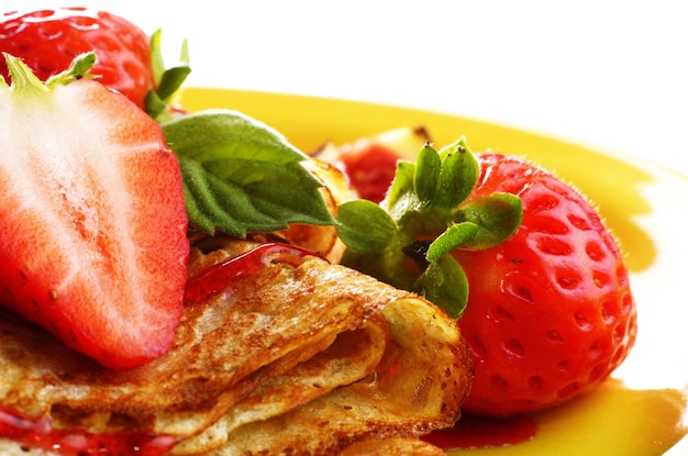 Crepes alla fragola con sciroppo e fichi sopra il primo piano bianco