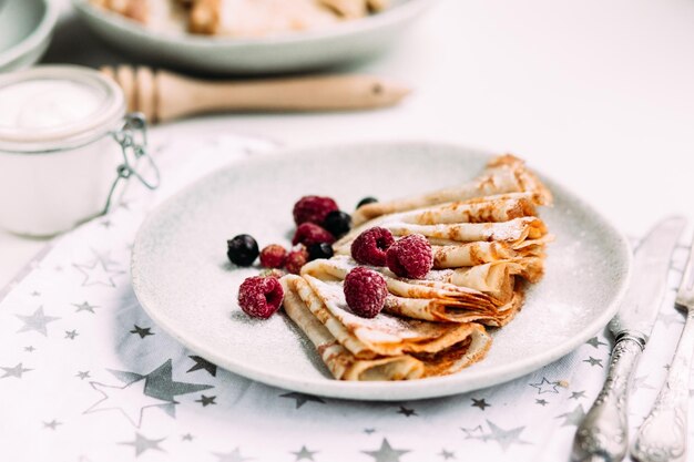 Crepes con ricotta fatta in casa, lamponi un piatto grigio