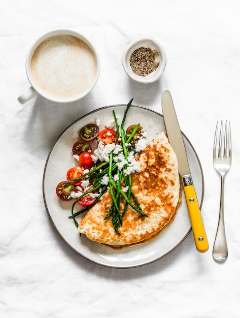 Crepes di farina d'avena senza farina con asparagi feta pomodorini e cappuccino deliziosa colazione dietetica su sfondo scuro vista dall'alto