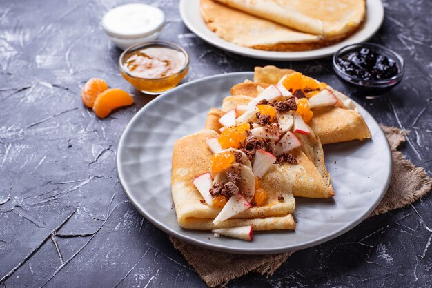 Crepes di frittelle con diversi tipi di frutta e cioccolato