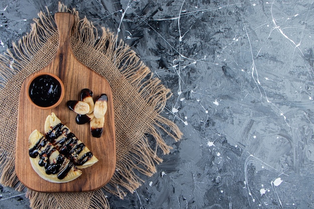Crepes fatte in casa con cioccolato e banana a fette su tavola di legno.