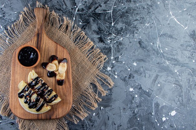 Crepes fatte in casa con cioccolato e banana a fette su tavola di legno.