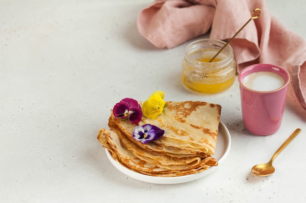 crepes francesi frittelle decorate con fiori una tazza di cappuccino e miele concetto di colazione des...