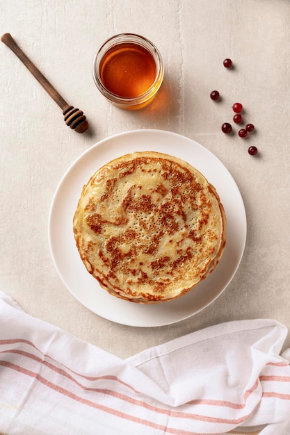 Crepes frittelle sottili con miele su un piatto bianco Sfondo marmoreo Vista dall'alto