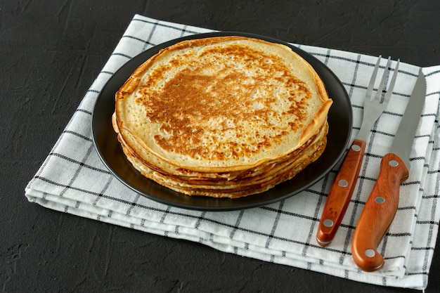 Crepes o Blini russi su fondo in legno in stile rustico. Crepes sottili fatte in casa per colazione o dessert.