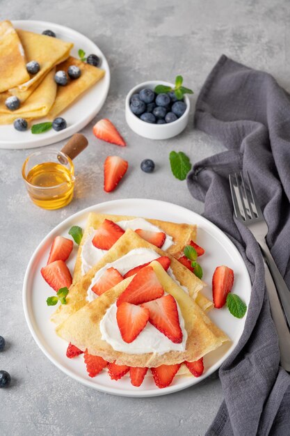 Crepes o frittelle sottili con crema di formaggio fragole fresche e miele Copia spazio