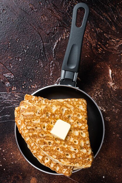 Crespelle francesi con burro in padella. Sfondo scuro. Vista dall'alto.