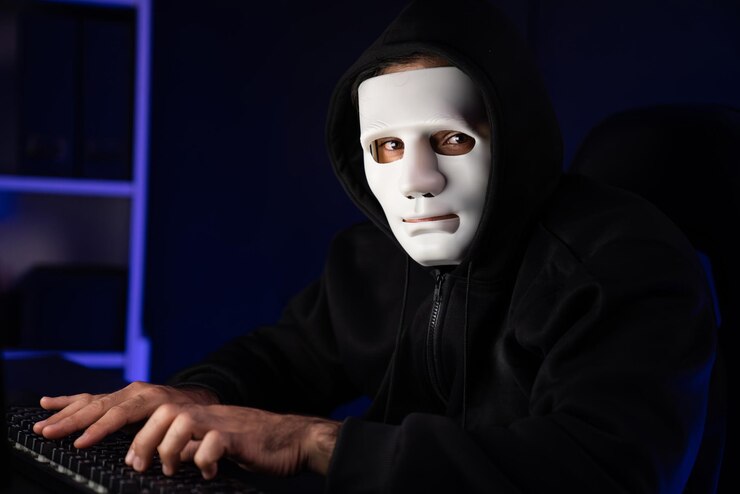 Foto criminale anonimo maschera guardando la telecamera mentre installa il virus sulla tastiera surmise