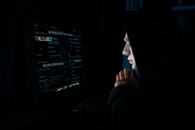 Criminali anonimi maschere hacker programmatore che cercano di avvicinarsi ai dati principali suppone