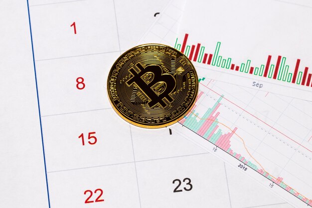 Criptovaluta. moneta bitcoin su un grafico e un calendario del mercato azionario.