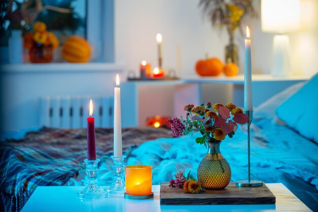 Crisantemo autunnale in vaso con candele accese in camera da letto